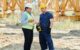 Man and woman in hard hats talk at a construction site